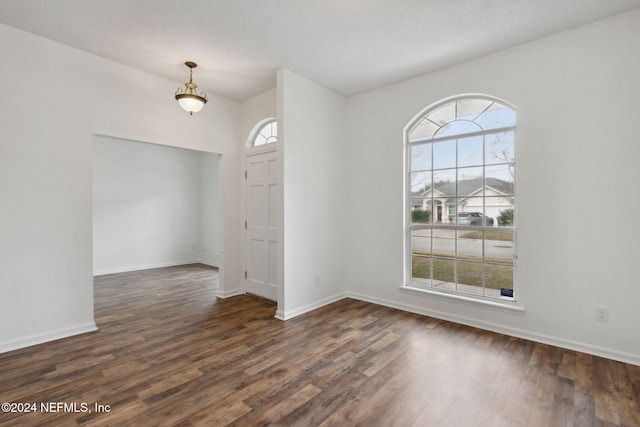 spare room with a textured ceiling and dark wood-type flooring