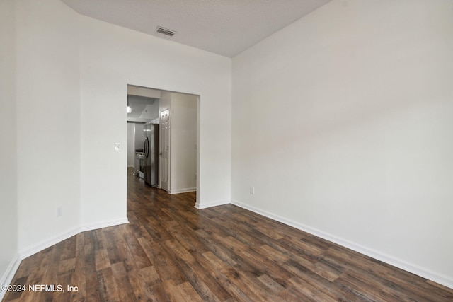 spare room with a textured ceiling and dark wood-type flooring