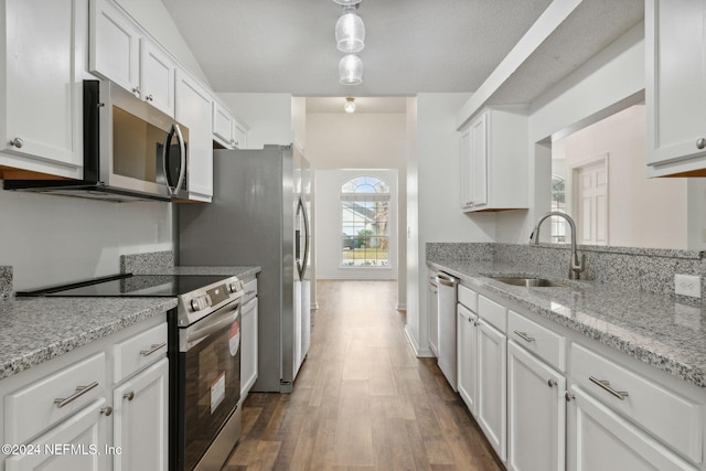 kitchen with white cabinetry, sink, stainless steel appliances, light stone counters, and dark hardwood / wood-style floors