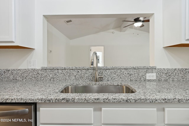 kitchen featuring light stone countertops, white cabinetry, lofted ceiling, and sink