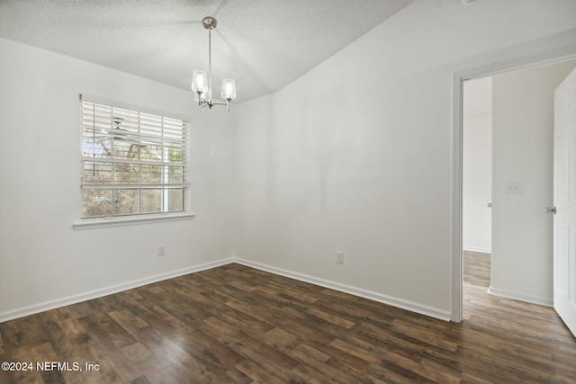 spare room with dark hardwood / wood-style flooring, a textured ceiling, and an inviting chandelier