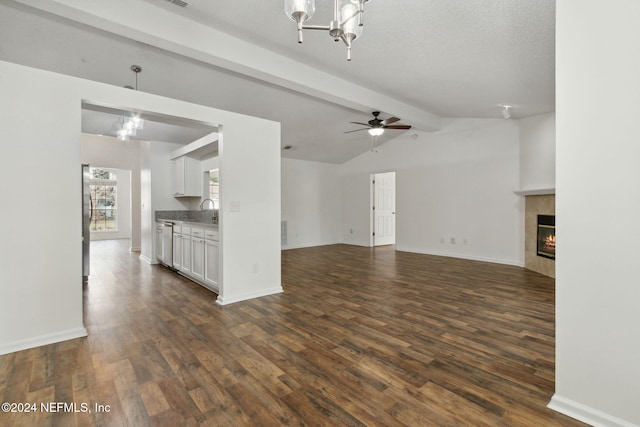 unfurnished living room with ceiling fan, sink, dark wood-type flooring, lofted ceiling with beams, and a textured ceiling