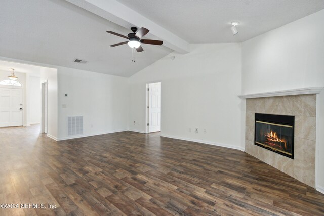 unfurnished living room featuring ceiling fan, a fireplace, lofted ceiling with beams, and dark hardwood / wood-style floors