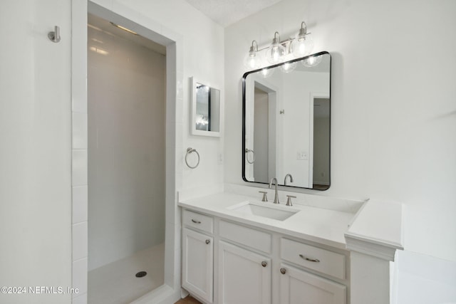 bathroom with a tile shower, vanity, and a textured ceiling