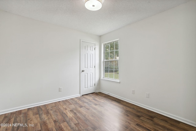 empty room with a textured ceiling and dark wood-type flooring