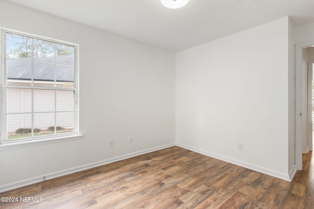 empty room featuring a textured ceiling, dark hardwood / wood-style flooring, and a wealth of natural light