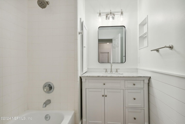 bathroom featuring tiled shower / bath combo and vanity