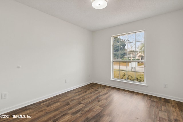 unfurnished room featuring a textured ceiling and dark hardwood / wood-style flooring