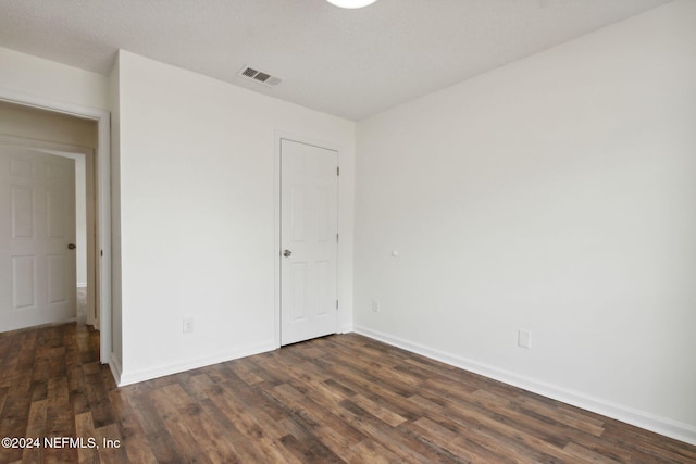 unfurnished room with a textured ceiling and dark wood-type flooring