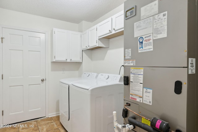 clothes washing area featuring cabinets, heating unit, a textured ceiling, washer and clothes dryer, and light tile patterned floors