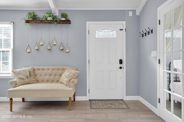 entryway featuring beamed ceiling, light hardwood / wood-style flooring, and ornamental molding