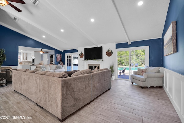 living room featuring vaulted ceiling with beams, ceiling fan, and light wood-type flooring