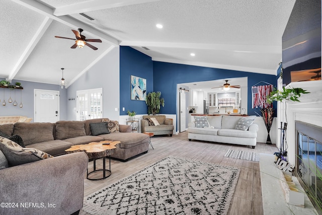 living room featuring beam ceiling, ceiling fan, high vaulted ceiling, a textured ceiling, and light wood-type flooring