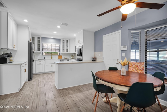 kitchen with backsplash, sink, light hardwood / wood-style floors, white cabinetry, and stainless steel appliances