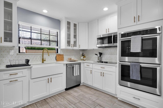 kitchen with decorative backsplash, sink, white cabinetry, and stainless steel appliances