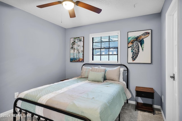 carpeted bedroom featuring ceiling fan and a textured ceiling