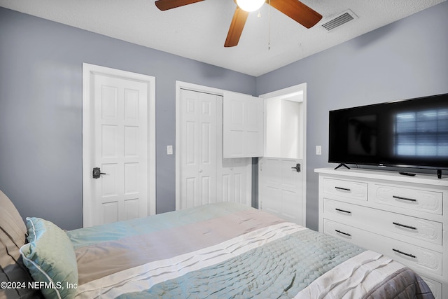 bedroom featuring multiple closets, ceiling fan, and a textured ceiling