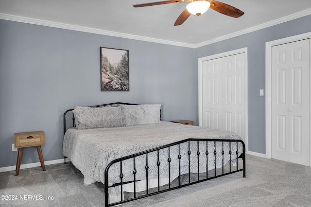 bedroom with carpet flooring, multiple closets, ceiling fan, and ornamental molding