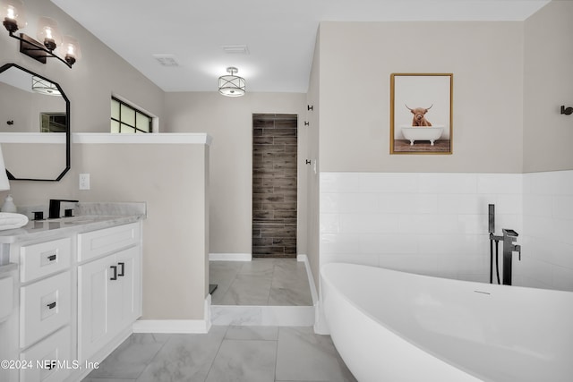 bathroom with a bath, vanity, and tile walls