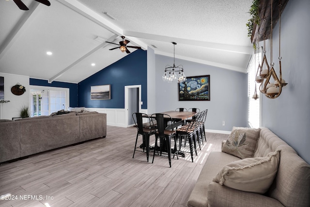 dining room featuring lofted ceiling with beams, a textured ceiling, ceiling fan with notable chandelier, and light hardwood / wood-style floors