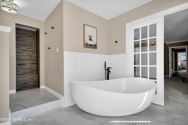 bathroom featuring a bath, tile walls, and crown molding