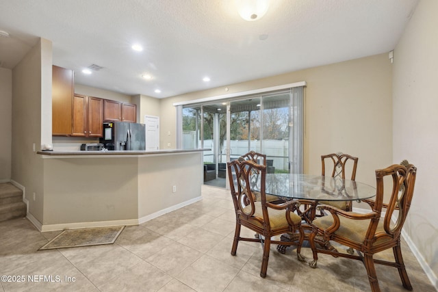 kitchen featuring light tile patterned flooring, kitchen peninsula, a textured ceiling, and stainless steel fridge with ice dispenser