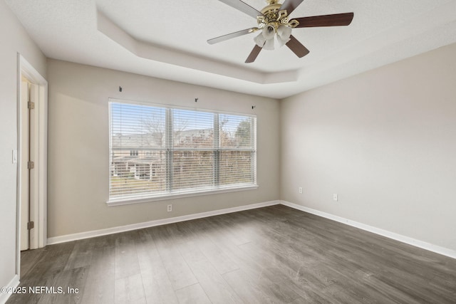 spare room featuring ceiling fan, a tray ceiling, and dark hardwood / wood-style flooring