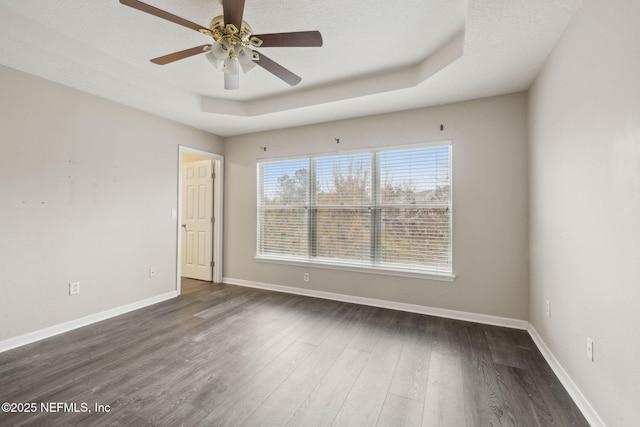 unfurnished room with dark hardwood / wood-style flooring, a textured ceiling, ceiling fan, and a tray ceiling