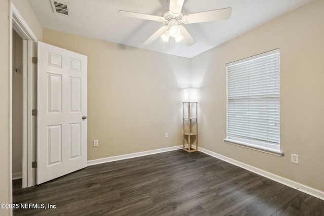 spare room featuring dark wood-type flooring and ceiling fan