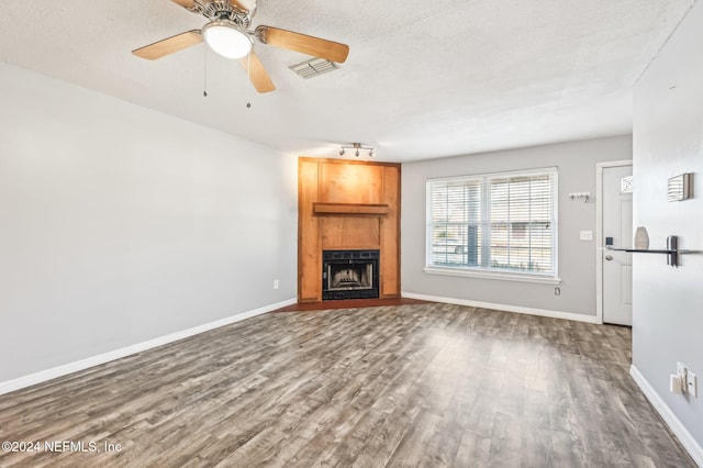 unfurnished living room with dark hardwood / wood-style flooring, a large fireplace, and a textured ceiling