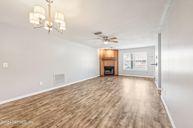 unfurnished living room with hardwood / wood-style flooring, a fireplace, and ceiling fan with notable chandelier