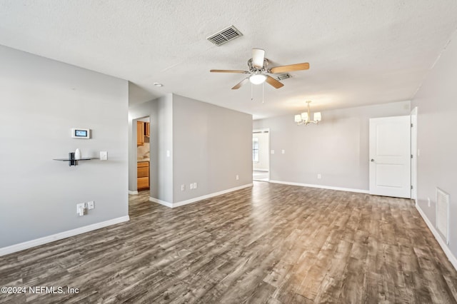 empty room featuring dark hardwood / wood-style flooring, ceiling fan with notable chandelier, and a textured ceiling