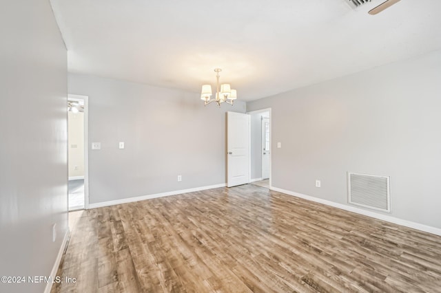 spare room featuring hardwood / wood-style flooring and a chandelier