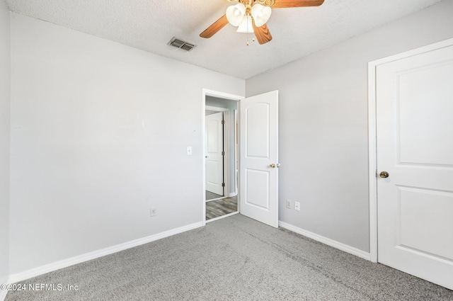 unfurnished bedroom featuring ceiling fan, carpet flooring, and a textured ceiling