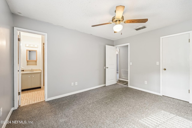 unfurnished bedroom featuring ensuite bath, carpet flooring, sink, ceiling fan, and a textured ceiling