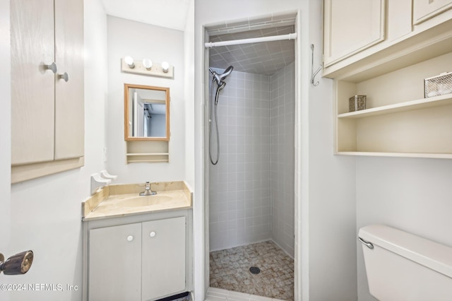 bathroom with vanity, toilet, and a tile shower