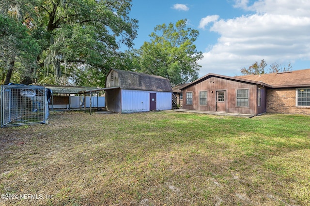 back of property with a carport, a yard, and a storage shed