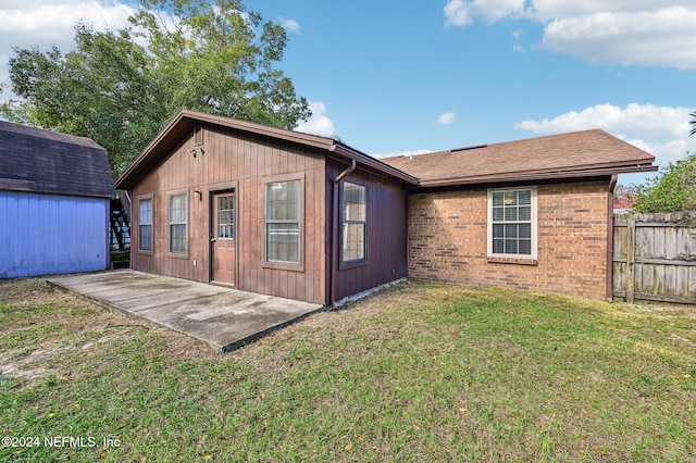 rear view of house featuring an outdoor structure, a patio area, and a lawn