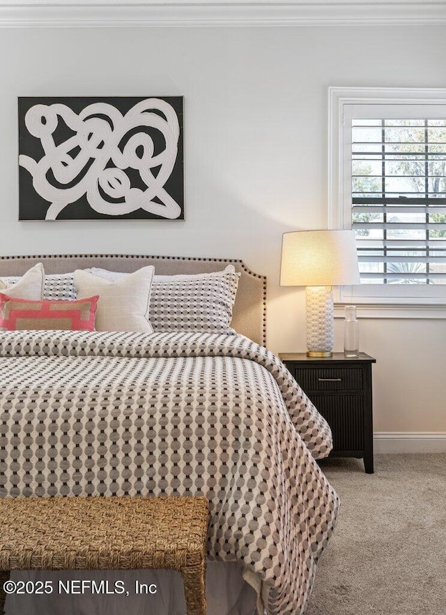 carpeted bedroom with ornamental molding and baseboards