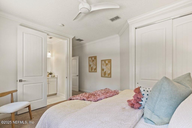 bedroom featuring a closet, visible vents, crown molding, and a textured ceiling