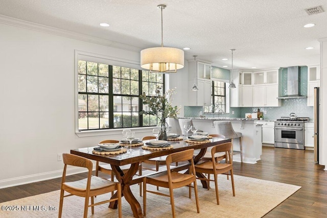 dining room with baseboards, visible vents, dark wood-style floors, ornamental molding, and a textured ceiling