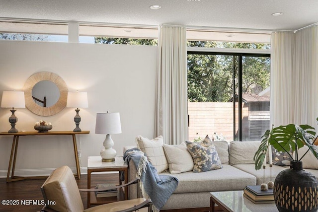 living area with a textured ceiling, recessed lighting, wood finished floors, baseboards, and floor to ceiling windows