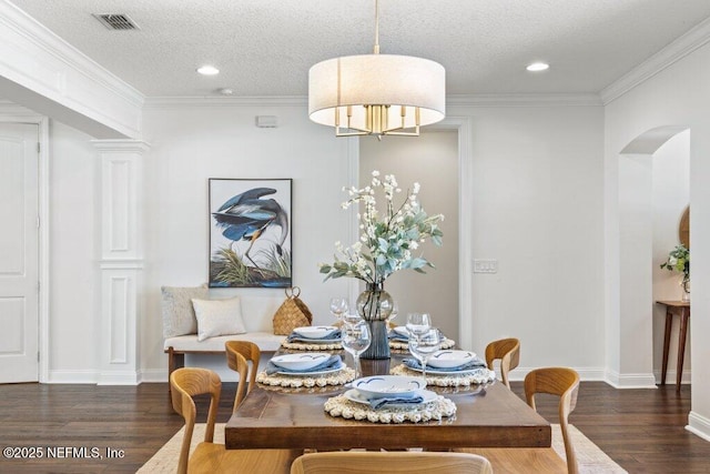 dining space featuring arched walkways, visible vents, a textured ceiling, and wood finished floors