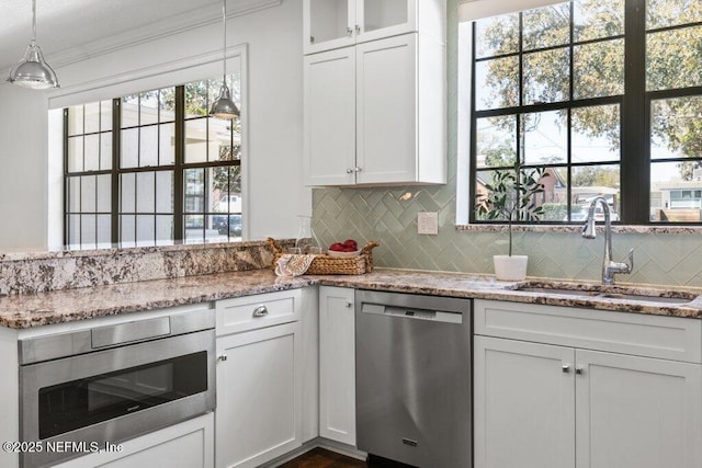 kitchen with appliances with stainless steel finishes, backsplash, a sink, and white cabinets