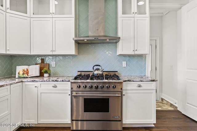 kitchen featuring light stone counters, white cabinetry, wall chimney range hood, and high end stainless steel range