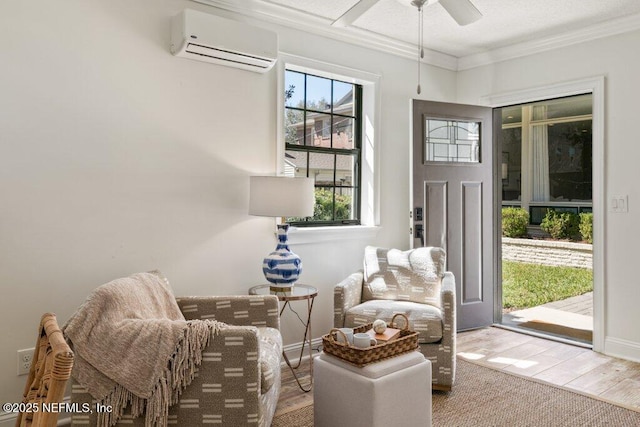 living area with wood finished floors, a ceiling fan, baseboards, an AC wall unit, and ornamental molding