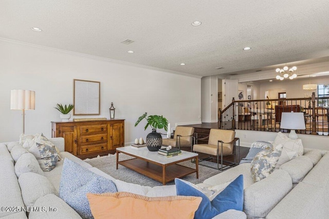 living room with crown molding, a textured ceiling, and a notable chandelier