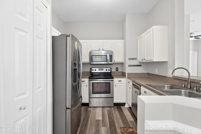 kitchen with white cabinets, appliances with stainless steel finishes, dark hardwood / wood-style floors, and sink