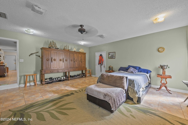 bedroom featuring ceiling fan, light tile patterned flooring, and a textured ceiling