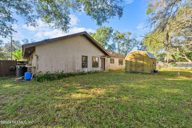 back of house featuring a storage unit and a lawn